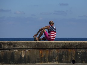 A man wearing a shirt with the stars and stripes sits on the Malecon in Havana, Cuba, Wednesday, April 18, 2018. Cuba's legislature opened today a two-day session that is to elect a successor to President Castro.