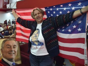 A supporter of Montenegro's former prime minister and long-ruling Democratic Party of Socialists leader Milo Djukanovic holds an American flag during a celebration after presidential elections in the Montenegro capital of Podgorica, Sunday, April 15, 2018. Montenegro's ruling party declared leader Milo Djukanovic the winner of Sunday's presidential election after preliminary projections showed he swept the vote and avoided a runoff.