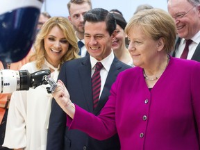 German chancellor Angela Merkel, right, Mexico's President Enrique Pena Nieto, center, and his wife Angelica Rivera de Pena, left, watch a robot arm at the IGB booth at the Hannover Fair, in Hannover, Germany, Monday, April 23, 2018.