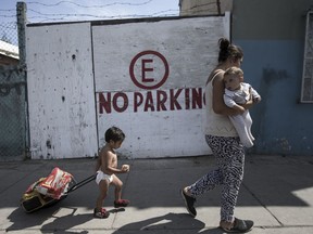 A Honduran migrant who is traveling with a caravan of Central American migrants walks with her two children to a shelter in Tijuana, Mexico, Wednesday, April 25, 2018. The caravan of mainly Central American migrants are planning to request asylum, either in the United States or Mexico.