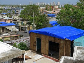 FILE - In this Oct. 19, 2017 file photo, homes in the Cantera area are covered with FEMA tarps, where buildings from the Hato Rey area stand in the background in San Juan, Puerto Rico. The U.S. government announced Tuesday, April 10, 2018 that it will award $18.5 billion worth of disaster recovery grants to Puerto Rico to help repair homes, businesses and its crumbling power grid as the U.S. territory struggles to recover from Hurricane Maria.