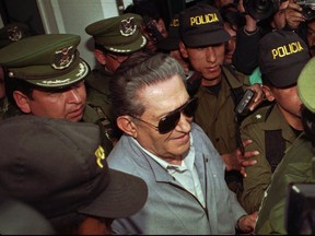 FILE  - In this  Jan 17 1997 file photo, Bolivia's jailed, ex-dictator Luis Garcia Meza is surrounded by police as he leaves the Copacabana clinic in La Paz, Bolivia after being hospitalized 72 hours for cardiac problems. The former military dictator, who was serving a 30-year prison sentence for a dozen murders carried out during his thirteen months in office from 1980-1981, died on Sunday, April 29, 2018.