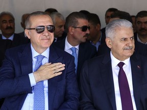 Turkey's President Recep Tayyip Erdogan, left, flanked by Turkey's Prime Minister Binali Yildririm, attends an opening ceremony for a rail commute line in Ankara, Turkey, Thursday, April 12, 2018. Erdogan says he will discuss ways of ending "the chemical massacre" in Syria during a telephone call with Russia's President Vladimir Putin, a day after he talked to President Donald Trump about Syria.