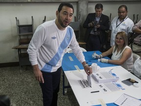 Guatemalan President Jimmy Morales looks to photographers as he casts his vote during a plebiscite on a border dispute with Belize, in Guatemala City, Sunday, April 15, 2018. Guatemalans are deciding whether their government should request the International Court of Justice to resolve the dispute that dates back to 1821 when Guatemala won independence from Spain and its border with the United Kingdom's territory was being decided. Guatemala recognized Belize's independence in 1992 but did not recognize its border.