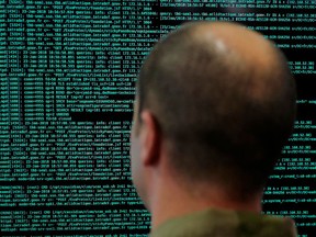 FILE - In this file photo taken on Jan. 23 2018, a solider watches code lines on his computer screen at the French Defense ministry stand during the International Cybersecurity forum in Lille, northern France. France has flagged more than 78,000 people as security threats in a database intended to let European police share information on the continent's most dangerous residents _ more than all other European countries put together _ according to an analysis by The Associated Press.