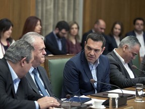 Greek Prime Minister Alexis Tsipras, centre, talks with Economy and Development Minister Yannis Dragasakis, second left, and Defense Minister Panos Kammenos during a cabinet meeting in Athens, Tuesday, April 3, 2018. Tsipras on Tuesday renewed a call on neighbor Turkey to release two Greek soldiers arrested on a border patrol last month.