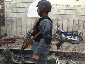 An Afghan police officer stands outside a voter registration center which was attacked by a suicide bomber in Kabul, Afghanistan, Sunday, April 22, 2018. Gen. Daud Amin, the Kabul police chief, said the suicide bomber targeted civilians who had gathered to receive national identification cards.