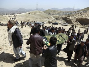 Men carry the coffin of a relative who died in Sunday's suicide attack at a voter registration center, in Kabul, Afghanistan, Monday, April 23, 2018. Taliban attacks in western Afghanistan killed 14 soldiers and policemen on Monday as residents in the capital, Kabul, prepared for the funerals of those killed in the horrific bombing by the Islamic State group on a voter registration center that left at least 57 dead the previous day.
