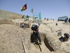 Afghan men prepare the graves for the victims of Sunday's suicide attack at a voter registration center, in Kabul, Afghanistan, Monday, April 23, 2018. Taliban attacks in western Afghanistan killed 14 soldiers and policemen on Monday as residents in the capital, Kabul, prepared for the funerals of those killed in the horrific bombing by the Islamic State group on a voter registration center that left at least 57 dead the previous day.