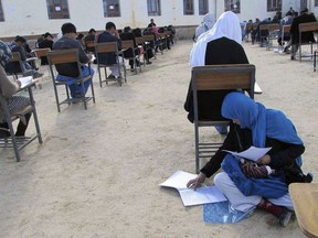 In this Friday, March 16, 2018 photo, Jahantab Ahmadi, 25, attend during at the university entrance exam in Daikundi in central Afghanistan. A picture of Afghan woman Jahantap Ahmadi posted on Facebook set her on a path to college. In the image she is seen sitting cross-legged on a classroom floor with her 2-month-old baby asleep on her lap as she takes her university entrance exam. At age 25 with three children under age 5 and a husband who can neither read nor write, Ahmadi had dreamed of going to college.
