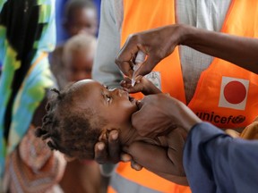 FILE- In this Saturday, Aug. 27, 2016, file photo, a health official from the United Nations International Children's Emergency Fund (UNICEF) administers a polio vaccine to a child at a camp for people displaced by Islamist extremists, in Maiduguri, Nigeria. The Boko Haram extremist group has disrupted efforts to eradicate polio in Nigeria, one of just three countries where the crippling disease remains endemic.