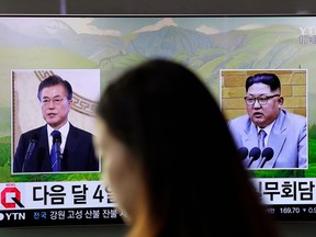 FILE - In this March 29, 2018, file photo, a visitor walks by a TV screen showing file footages of South Korean President Moon Jae-in, left, and North Korean leader Kim Jong Un, right, during a news program at the Seoul Railway Station in Seoul, South Korea. The rival Koreas started on Thursday, April 5, 2018, preparatory talks to set up a summit later this month between North Korean leader Kim Jong Un and South Korean President Moon Jae-in amid a global diplomatic push to resolve tensions over the North's nuclear program.