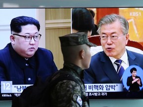 FILE - In this April 18, 2018 file photo, a South Korean marine soldier walks by a TV screen showing file footage of South Korean President Moon Jae-in and North Korean leader Kim Jong Un, left, during a news program at the Seoul Railway Station in Seoul, South Korea. While North Korea declared this past weekend it would stop nuclear and intercontinental ballistic missile tests and shut down its nuclear test site, it did not indicate it will give up its nuclear arsenal or halt its production of missiles. Moon and later President Donald Trump are still likely to find it very difficult to persuade Kim to dismantle his entire arsenal, which includes purported thermonuclear weapons and developmental ICBMs.