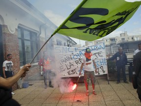 A striking train worker holds a flair during a demonstration, in Clichy, east of Paris, Monday, April 23, 2018. Striking French train workers have occupied a building in a surprise protest against President Emmanuel Macron's reforms of the state-run rail company. Most French trains were cancelled Monday on the ninth day of a nationwide strike over a plan to take away worker benefits to allow the company to open up to competition.