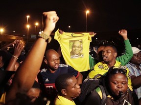 Supporters of former president Jacob Zuma hold a tee-shirt with his picture, attend a night vigil on the eve of Zuma's appearance in the High Court in Durban, South Africa, Thursday, April 5, 2018. Former South African president Jacob Zuma has been summoned to appear in court on April 6 on charges of fraud, racketeering and money laundering.