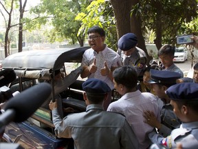 Reuters journalists Wa Lone, center, talks to journalists from police truck as he leaves the court after their trial in Yangon, Myanmar Friday, April 20, 2018. The prosecution of two Myanmar journalists accused of violating a state secrets law by acquiring official documents given to them by police has suffered a setback after a police officer testified that he and his colleagues were ordered to entrap the reporters.