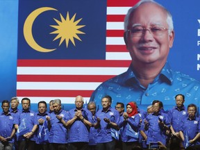 In this April 7, 2018 photo, Malaysia's Prime Minister and President of the ruling party coalition "National Front", Najib Razak, center, prays during launching event for upcoming general elections in Kuala Lumpur, Malaysia. Prime Minister Najib unveiled a lavish election manifesto with cash benefits targeting rural ethnic Malays, his key voting bloc, as he faces an unprecedented challenge from a revived opposition led by his former mentor, Mahathir Mohamad.