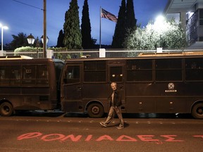 A man walks in front of the U.S. embassy where the word " Murderers " is written on the street by supporters of the Greek Communist party, in Athens, Saturday, April 14, 2018. Thousands of people marched to the embassy during an anti-war rally opposing the military strikes by western countries in Syria.