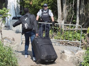 An asylum seeker is confronted by an RCMP officer as he crosses the border into Canada from the United States on August 21, 2017 near Champlain, N.Y.