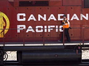 A Canadian Pacific Railway employee walks along the side of a locomotive in a marshalling yard in Calgary, Wednesday, May 16, 2012.
