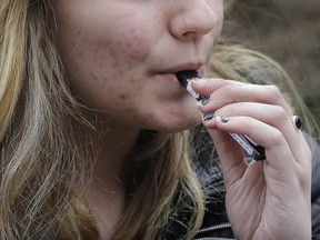 An unidentified 15-year-old high school student uses a vaping device near a school's campus.