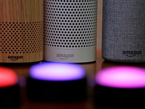 Amazon Echo and Echo Plus smart speakers, behind, sit near illuminated Echo Button devices.