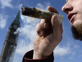 A man smokes a marijuana joint during the annual 4/20 marijuana celebration on Parliament Hill in Ottawa on April 20, 2018.