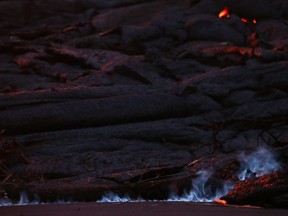 Blue flames of methane gas escape from a crack near a Kilauea volcano fissure in Leilani Estates, on Hawaii's Big Island, on May 23, 2018 in Kapoho, Hawaii.