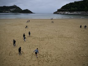 People walk along the sand at La Concha beach, in the Basque city of San Sebastian, northern Spain, Wednesday, May 2, 2018.