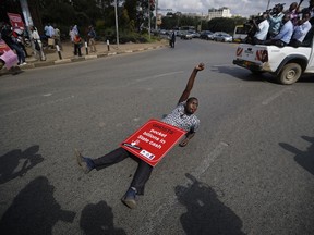 A protester lies down on the street during an anti-corruption demonstration by hundreds of protesters who marched to the Parliament and Supreme Court in downtown Nairobi, Kenya, Thursday, May 31, 2018. Kenya's leader is under increasing pressure as outrage grows over a number of corruption scandals involving tens of millions of dollars revealed in recent weeks around the ministries of health, energy, agriculture, public service and youth.