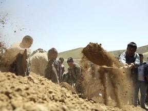 Afghan men bury a victim of Sunday's suicide attack at a voter registration center, in Kabul, Afghanistan, Monday, April 23, 2018. Taliban attacks in western Afghanistan killed 14 soldiers and policemen on Monday as residents in the capital, Kabul, prepared for the funerals of those killed in the horrific bombing by the Islamic State group on a voter registration center that left at least 57 dead the previous day.