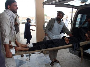 An Afghan wounded man lays on a trolley as others rush him to a hospital following blast at a voter registration centre in Khost Province on May 6, 2018.