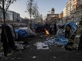 In this file photo taken on February 23, 2018 migrants, mainly from Afghanistan, warm themselves up around a bonfire as freezing temperatures settle along the canal Saint-Martin in Paris.