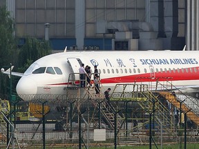 This photo taken on May 14, 2018 shows employees checking a Sichuan Airlines Airbus A319 after an emergency landing, as a broken cockpit window is covered, in Chengdu in China's northwestern Sichuan province.