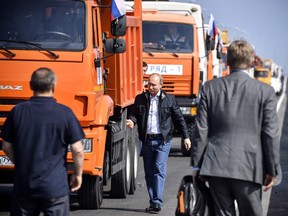 Russian President Vladimir Putin walks away from a construction truck after he drove the vehicle across the new 19-kilometre road-and-rail Crimean Bridge over the Kerch Strait that links mainland Russia to Moscow-annexed Crimea on May 15, 2018.