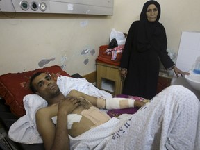 Marwan Shtewi, 32, lies on the bed while his mother's Fatma, stands near him at the surgery's ward of Shifa hospital in Gaza City, Wednesday, May 16, 2018. Shtewi was shot in his hand and abdomen by Israeli troops during a protest east of Gaza City on Monday. With few prospects and little to fear, Shtewi is among the crowds of young men who put themselves on the front lines of violent protests along the border with Israel, risking their lives in a weekly showdown meant to draw attention to the dire conditions of Gaza.