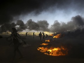 Palestinian protesters burn tires during a protest at the Gaza Strip's border with Israel, east of Khan Younis, Tuesday, May 15, 2018. Israel faced a growing backlash Tuesday and new charges of using excessive force, a day after Israeli troops firing from across a border fence killed dozens of Palestinians and wounded more than 2,700 at a mass protest in Gaza.