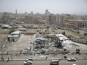 People stand in front of a petrol station after it was hit by Saudi-led airstrikes in Sanaa, Yemen, Sunday, May 27, 2018. Yemeni security officials say a Saudi-led coalition airstrike in the capital has killed at least four civilians and wounded over 10 others.