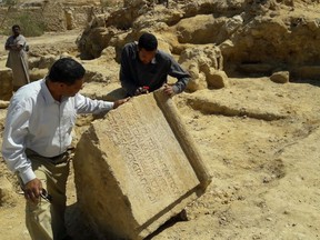 This undated photo released by the Egyptian Ministry of Antiquities, shows archaeologists examining an ancient stone found among the remains of a temple dating back to the second century, in the country's western desert, some 50 km west of Siwa Oasis, Egypt. The ministry said Thursday, May 10, 2018, that the temple, dates back to the reign of Roman Emperor Antoninus Pius. (Egyptian Ministry of Antiquities via AP)