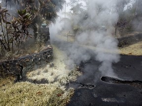 Steam and sulfur rises from cracks in Moku Street at the head of a driveway in Leilani Estates, Tuesday, May 8, 2018, in Pahoa, Hawaii.