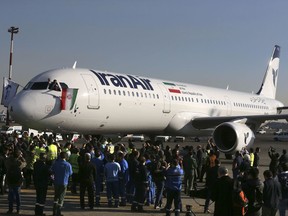 FILE - In this Jan. 12, 2017 file photo, the pilot of Iran Air's new Airbus plane waves a national flag after landing at Mehrabad International Airport in Tehran, Iran. From brand-new airplanes to oilfields, billions of dollars of deals stand on the line for international corporations as President Donald Trump weighs whether to pull America out of Iran's nuclear deal with world powers.