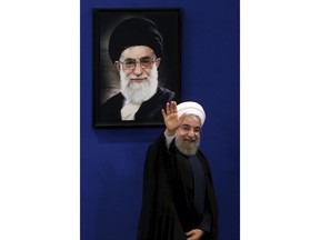 FILE - In this Aug. 29, 2015 file photo, Iran's President Hassan Rouhani waves to reporters at the conclusion of a press conference in Tehran, Iran. President Donald Trump is weighing whether to pull the U.S. out of Iran's nuclear deal, a 2015 agreement that capped over a decade of hostility between Tehran and the West over its atomic program. A picture of Supreme Leader Ayatollah Ali Khamenei hangs on the wall behind Rouhani.