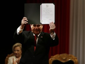 Paraguay's President Horacio Cartes holds up a certificate declaring him senator-elect during a ceremony in Asuncion, Paraguay, Friday, May 25, 2018. Cartes should resign before June 30 when the new parliamentarians will be sworn in. It is unknown when Cartes will present his resignation as the country's president before the current Congress that should accept or reject it.