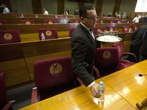 A steward removes bottled water and glasses after lawmakers suspended a special session to decide on whether to accept the resignation of President Horacio Cartes, for lack of a quorum, in Asuncion, Paraguay, Wednesday, May 30, 2018. Cartes, whose presidential term is coming to an end, is seeking resignation so he can be sworn-in to his newly-elected office of senator on June 30.