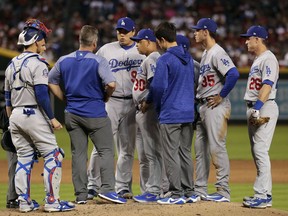 Los Angeles Dodgers starting pitcher Hyun-Jin Ryu, center, talks with a trainer after an injury during the first inning of the team's baseball game against the Arizona Diamondbacks on Wednesday, May 2, 2018, in Phoenix. Ryu left the game.