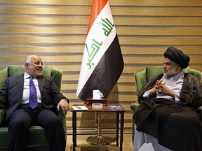 In this photo provided by the Iraqi government, Iraqi Prime Minister Haider al-Abadi, left, meets with Shiite cleric Muqtada al-Sadr in the heavily fortified Green Zone in Baghdad, Iraq, early Sunday, May 20, 2018. Shiite cleric Muqtada al-Sadr, whose coalition won the largest number of seats in Iraq's parliamentary elections, says the next government will be "inclusive." The May 12 vote did not produce a single bloc with a majority, raising the prospect of weeks or even months of negotiations to agree on a government. (Iraqi Government via AP)