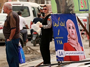 In this Sunday, April 22, 2018 photo, a poster of a woman candidate for parliamentary elections at a bus stop in Baghdad, Iraq. Iraqi women running for parliament this month are undaunted, despite many challenges they face ahead of the May 12 elections _ including unprecedented smear campaigns complete with sex videos that forced some to withdraw from the race.