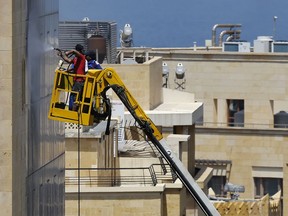 Workers wash windows on the downtown building where Lebanese lawmakers have their offices, in Beirut, Lebanon, Monday, May 21, 2018. The 128 members of the newly elected parliament will meet this week.