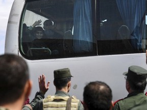 In this photo released by the Syrian official news agency SANA, released Syrian citizens who were held for years by al-Qaida-linked fighters, sit in a bus as they wave to the government forces soldiers upon their arrival at a government-controlled checkpoint, near Aleppo, Syria, Tuesday, May 1, 2018 . More than three dozen Syrians held for years by al-Qaida-linked insurgents in the country's northwest were released on Tuesday as part of a deal to hand over areas around Damascus back to the government, state media reported. (SANA via AP)
