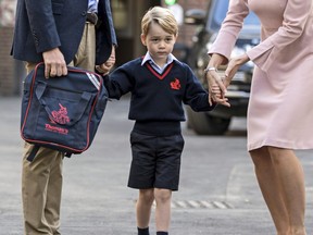 In this Thursday, Sept. 7, 2017 file photo, Britain's Prince William accompanies Prince George as he is met by Helen Haslem — the head of the lower school — on arrival for his first day of school at Thomas's school in Battersea, London.